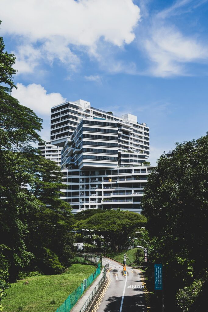 Contemporary apartment buildings in verdant Singapore landscape under a clear blue sky.