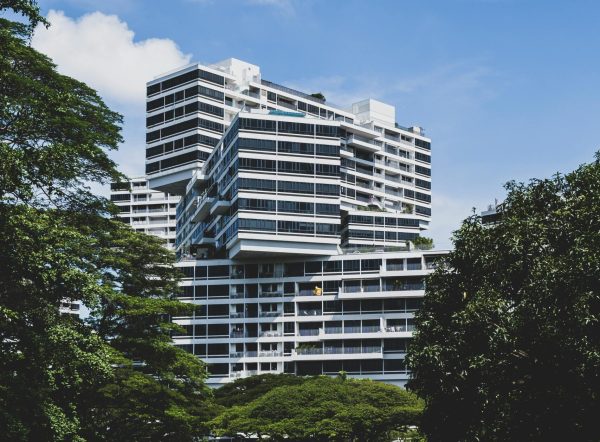 Contemporary apartment buildings in verdant Singapore landscape under a clear blue sky.